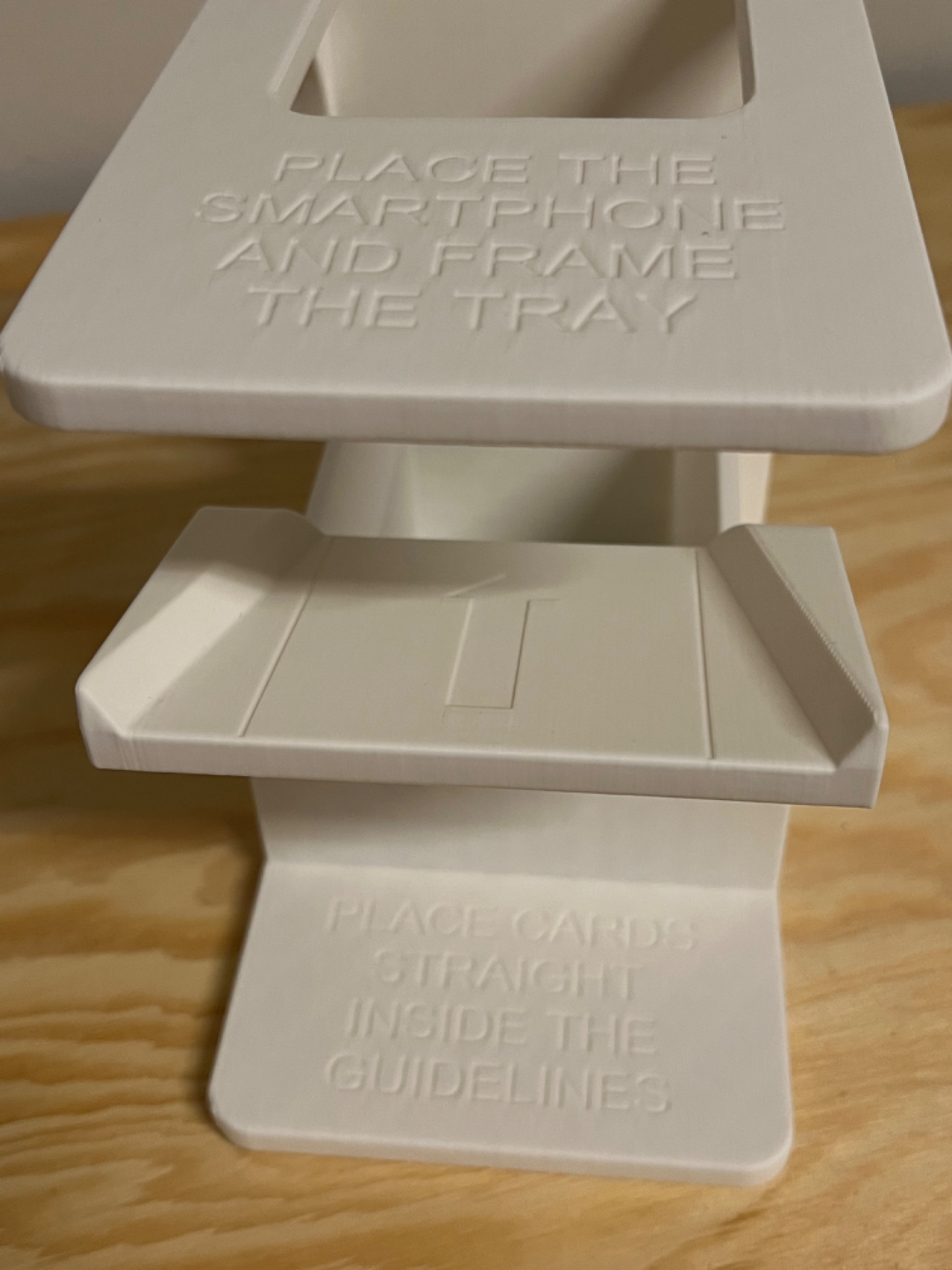 Lunqo 3D printed smartphone and card holder with embossed setup instructions on wood surface