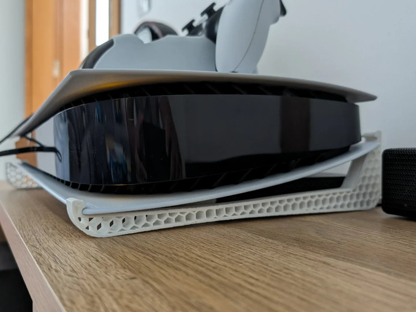 3D printed white honeycomb stand supporting a gaming console on a wooden surface