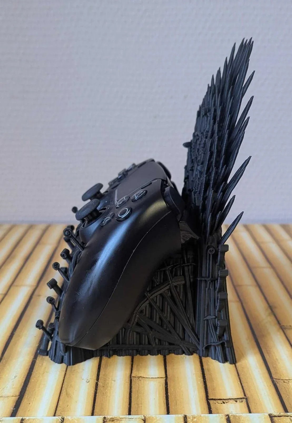 3D printed Iron Throne inspired controller stand with black gamepad on wood surface