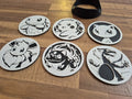 Six 3D printed round coasters with detailed designs of popular creatures, displayed on wood surface