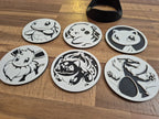 Six 3D printed round coasters with detailed designs of popular creatures, displayed on wood surface