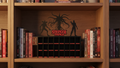 Wooden bookshelf with books and a 'Stranger Things' decorative item.