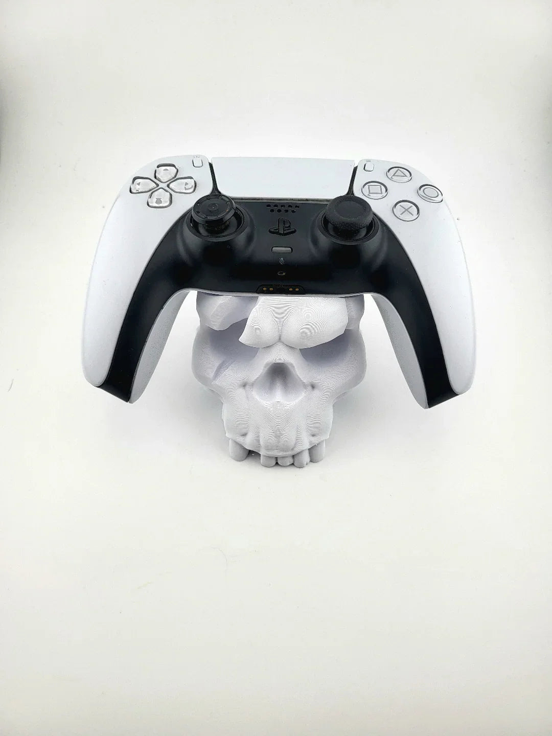 3D printed skull-shaped stand holding a PlayStation controller, modern minimalist style