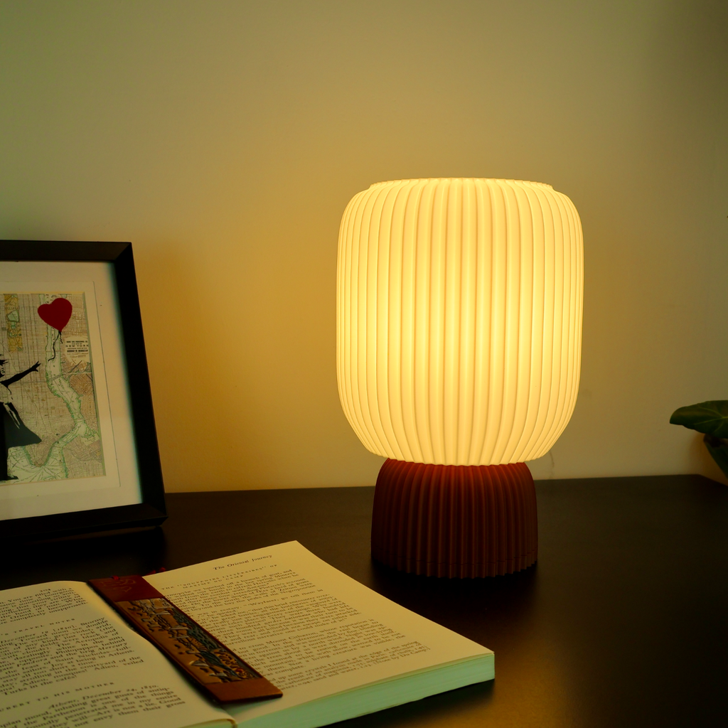 Modern 3D printed table lamp with ribbed shade on desk beside book and framed art, Lunqo design
