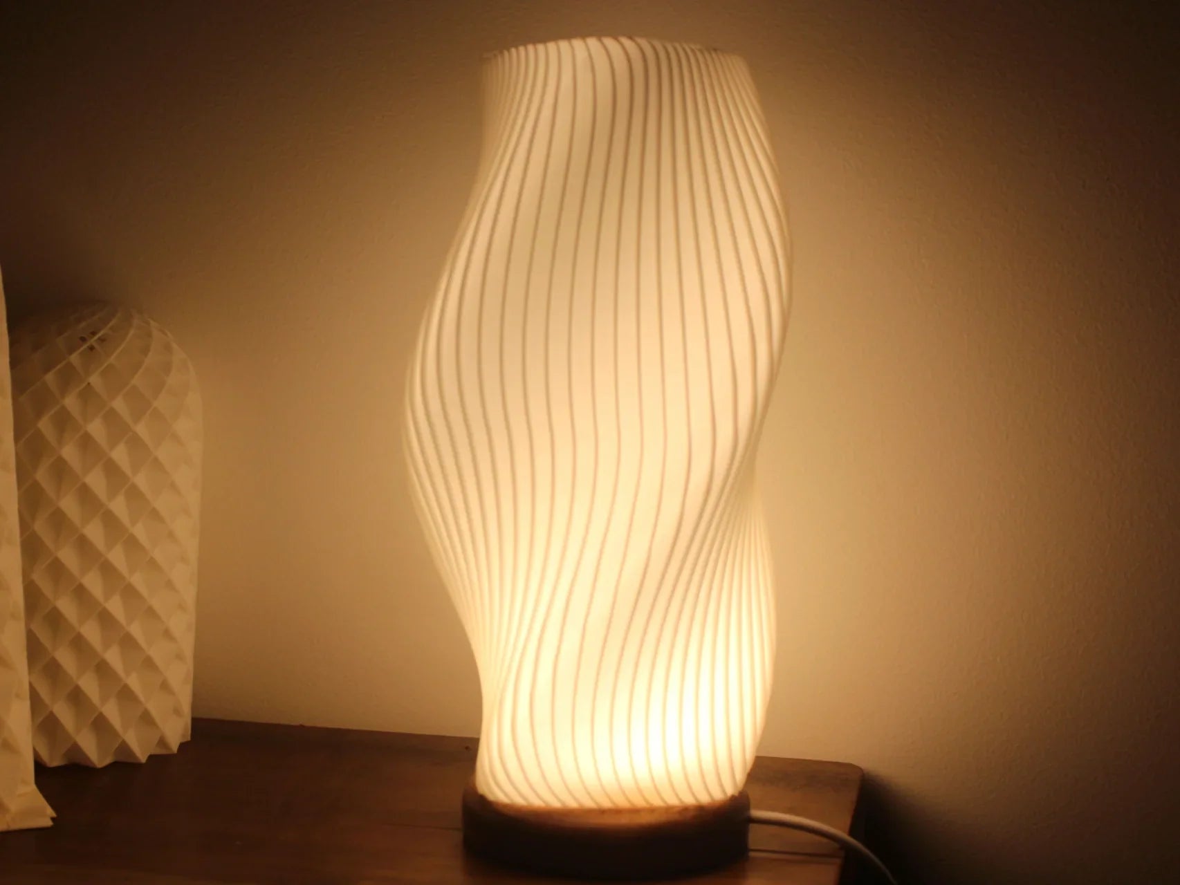 White textured table lamp on a wooden surface with a warm glow.