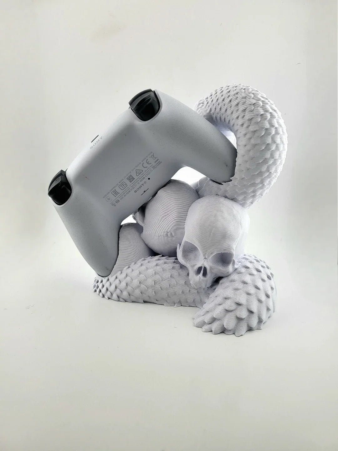 3D printed white serpent and skull controller stand holding a PlayStation controller, Lunqo design