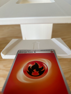 3D printed white card stand holding a vivid Pokémon fire energy card on wooden surface