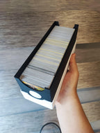 Hand holding a 3D printed black and white card deck box with trading cards inside