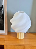 White textured table lamp on a wooden surface with a neutral background