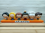 Figurines of characters from a popular TV show on an orange stand with 'F.R.I.E.N.D.S' label.