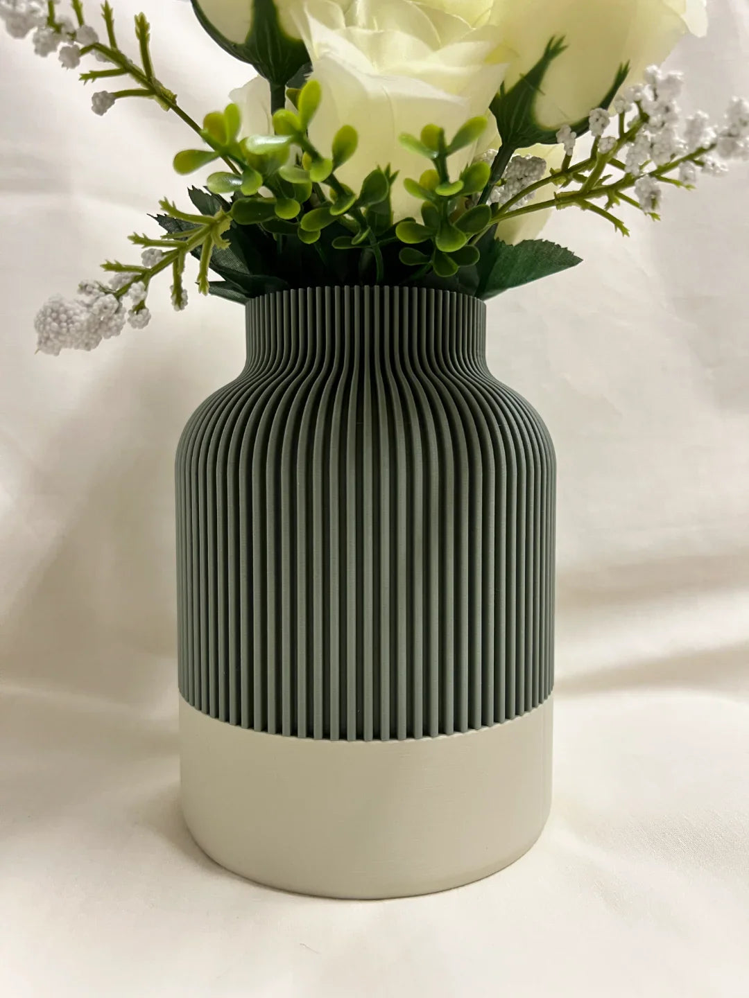 Green textured vase with white flowers on a white background