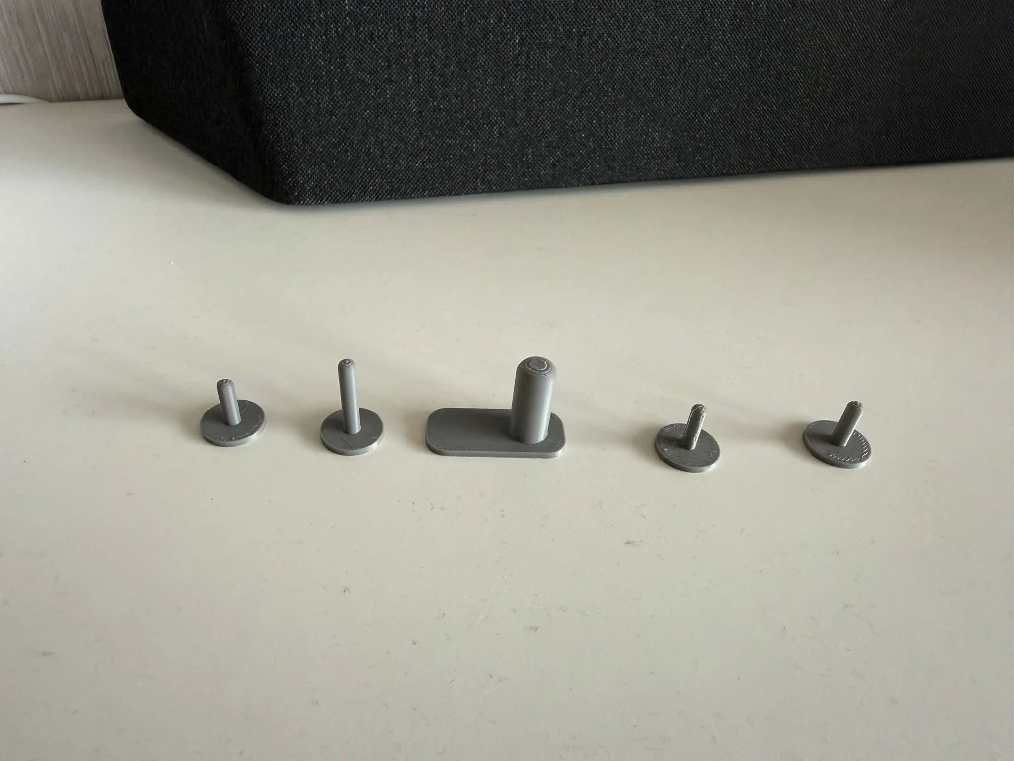 Five plastick hooks on a light surface with a dark textured object in the background