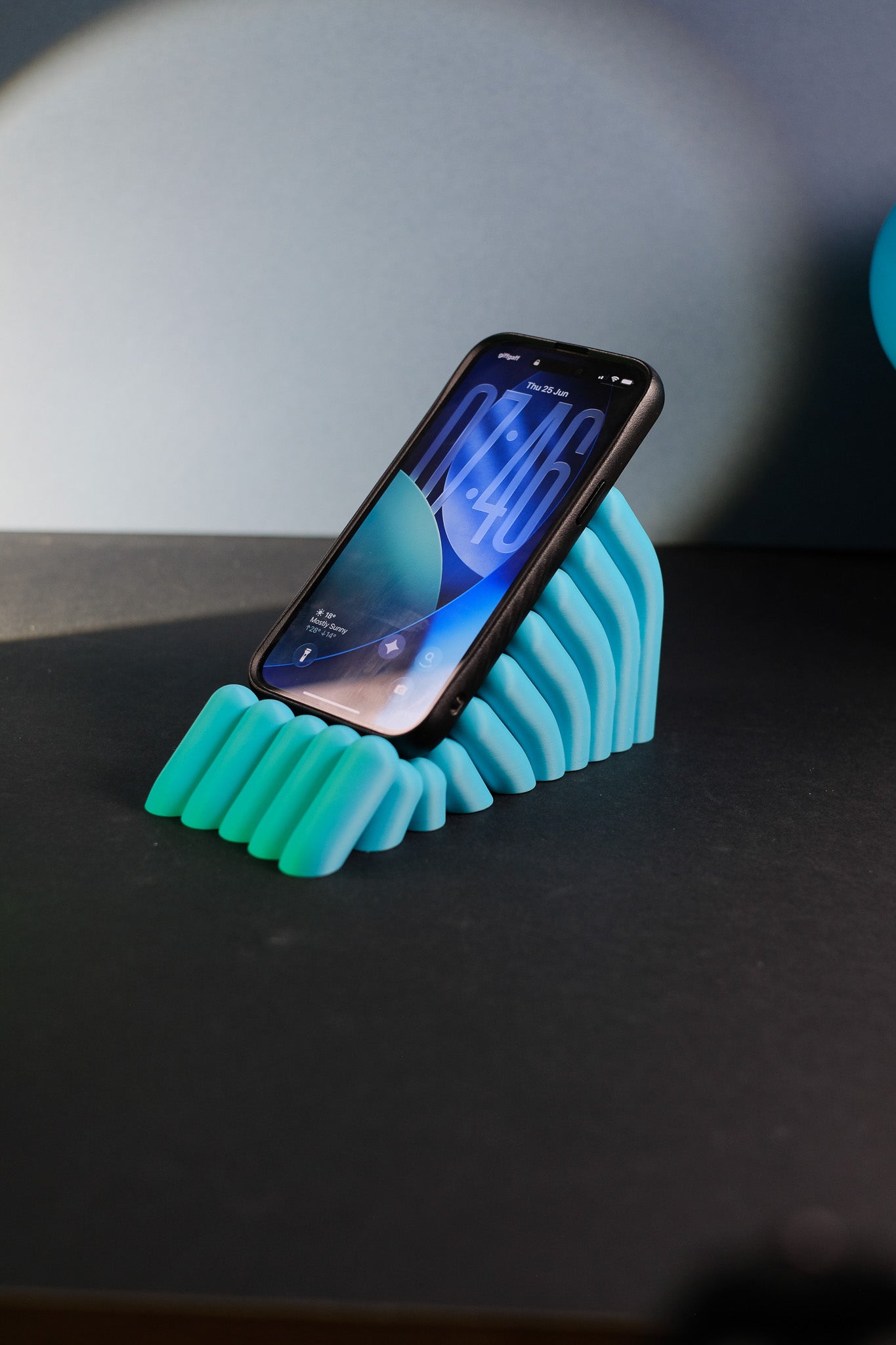 Mobile phone stand styled on a desk with its sculptural bobble texture visible.