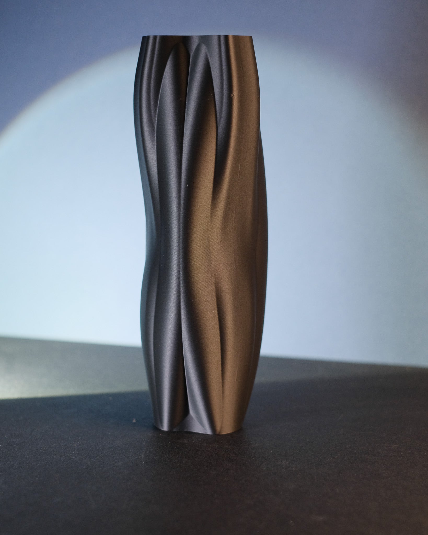 Black sculptural vase shown from an alternate angle to highlight its organic curves.