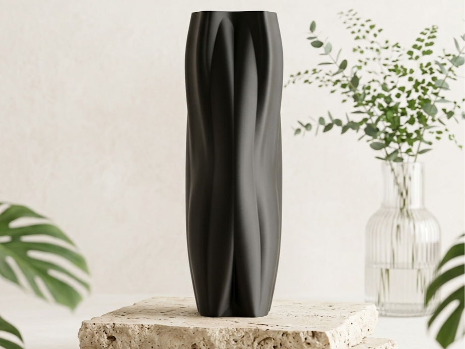 Black Flowganic sculptural vase styled on a stone plinth in a bright interior.