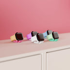 Mini Wibble Apple Watch charger stands in several colours displayed on a shelf