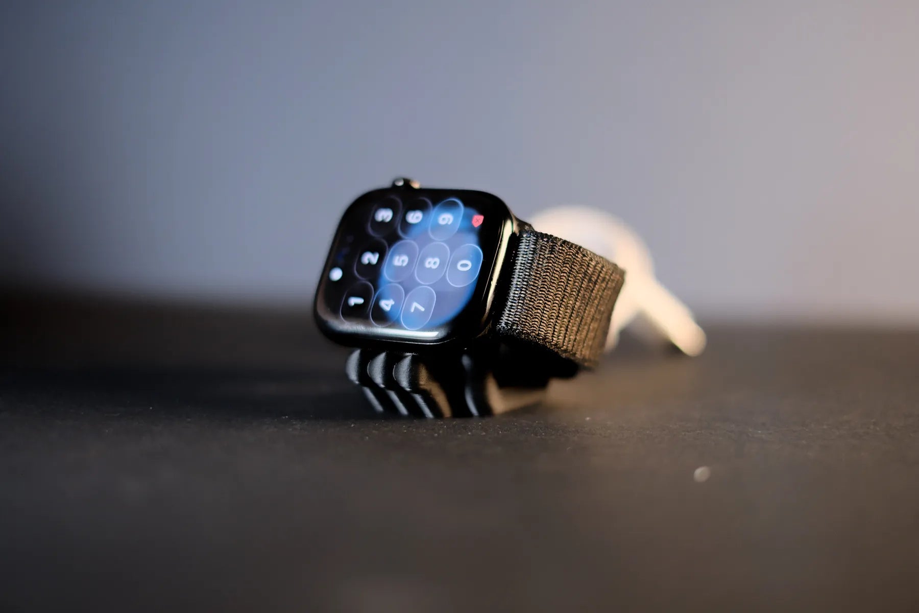 Angled close-up of a black Mini Wibble Apple Watch charger stand holding a watch