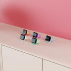Mini Wibble Apple Watch charging stands arranged across a shelf in multiple colours