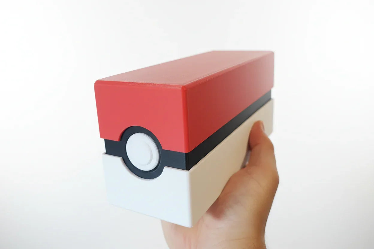Red, white, and black rectangular object resembling a Poké Ball held by a hand.