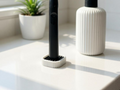 White ribbed electric toothbrush stand with a black drainage insert beside a bathroom sink