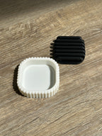 White outer stand and black removable drainage insert displayed separately on a wooden surface