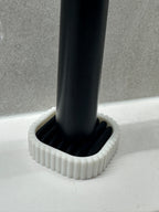 Close view of a black electric toothbrush base seated in the removable ribbed drainage insert