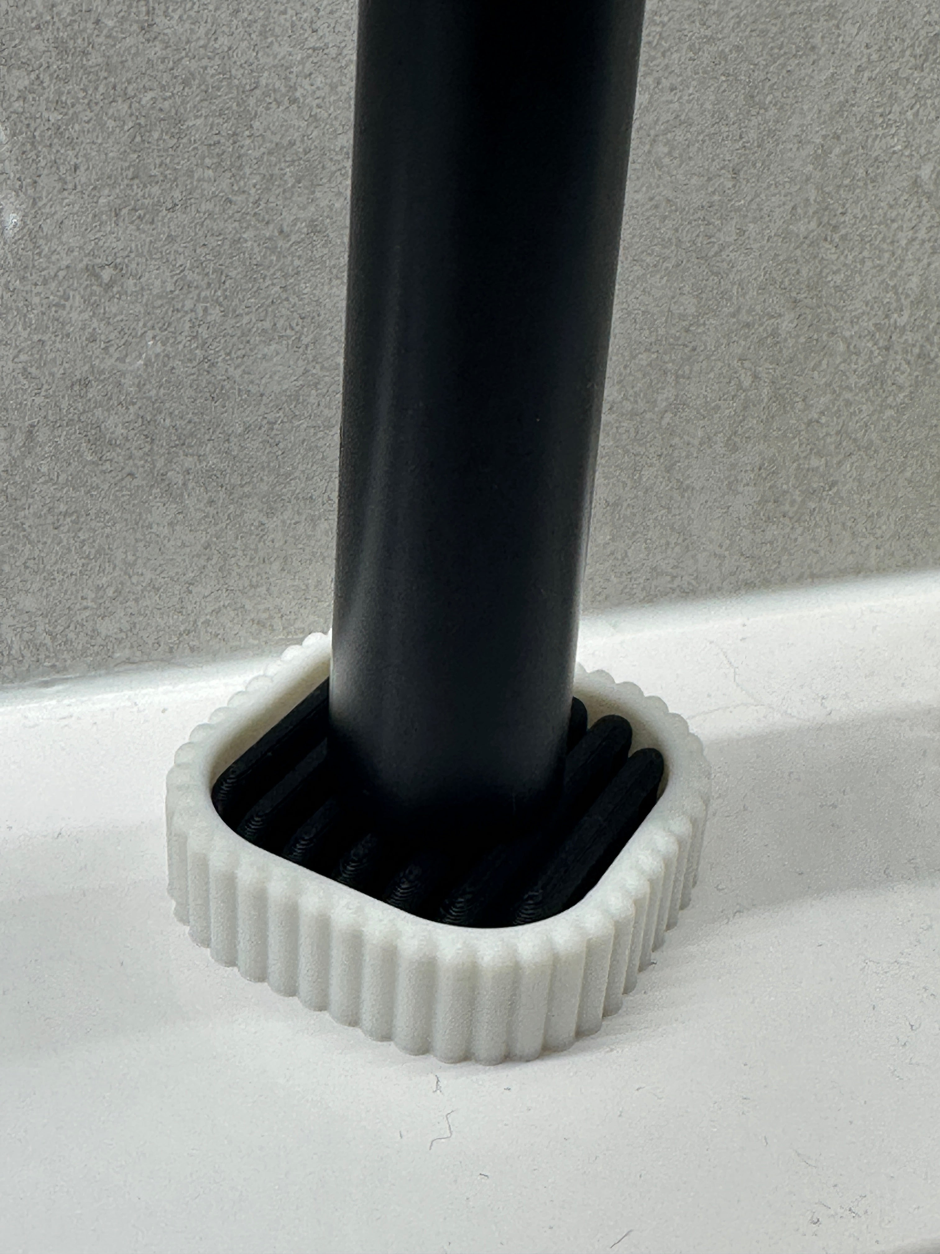 Close view of a black electric toothbrush base seated in the removable ribbed drainage insert