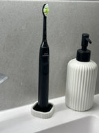 White and black electric toothbrush draining stand arranged on a clean bathroom counter