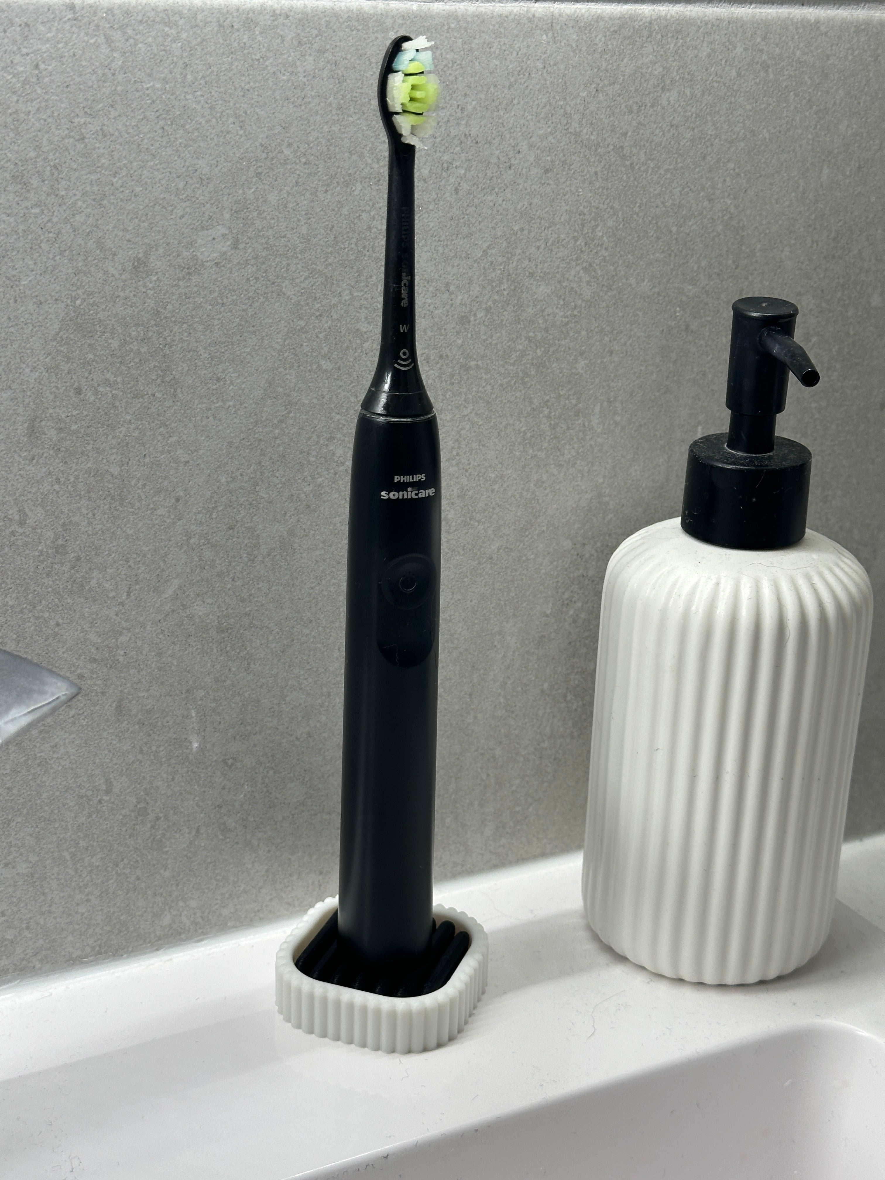 White and black electric toothbrush draining stand arranged on a clean bathroom counter