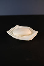 White Rippl soap dish with soap shown on a clean dark bathroom surface.