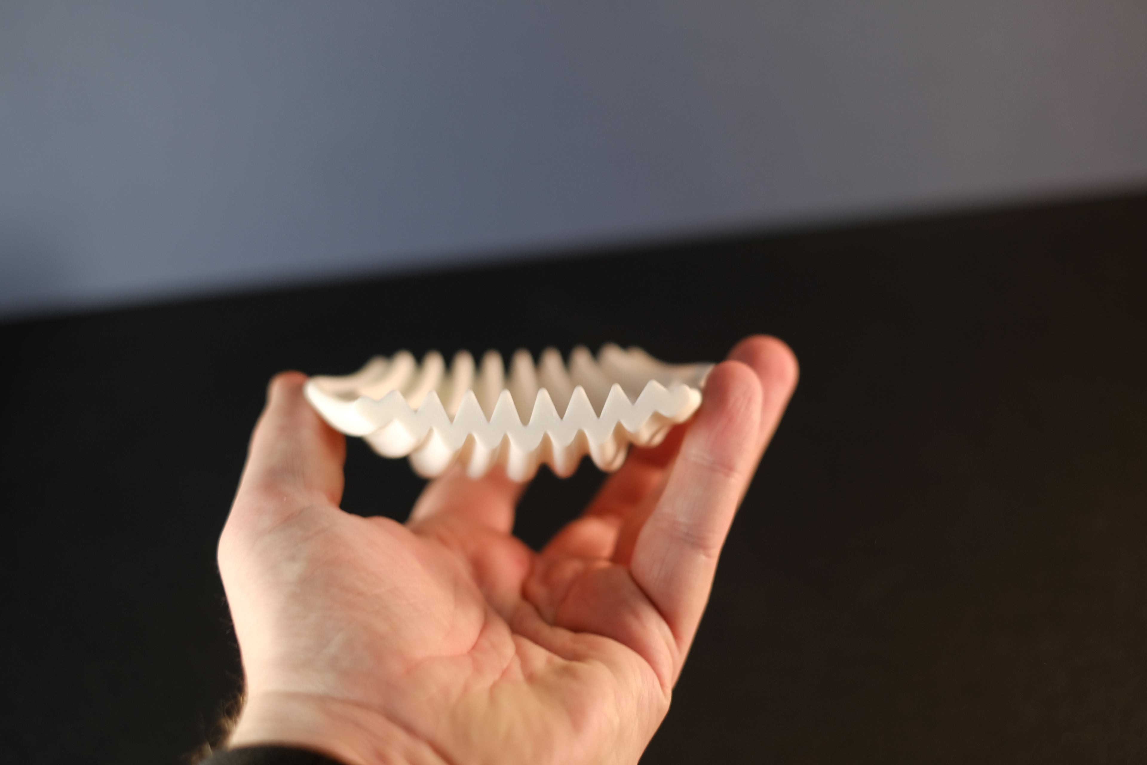 Side profile of the rippled soap dish held in hand, showing its open drainage form.