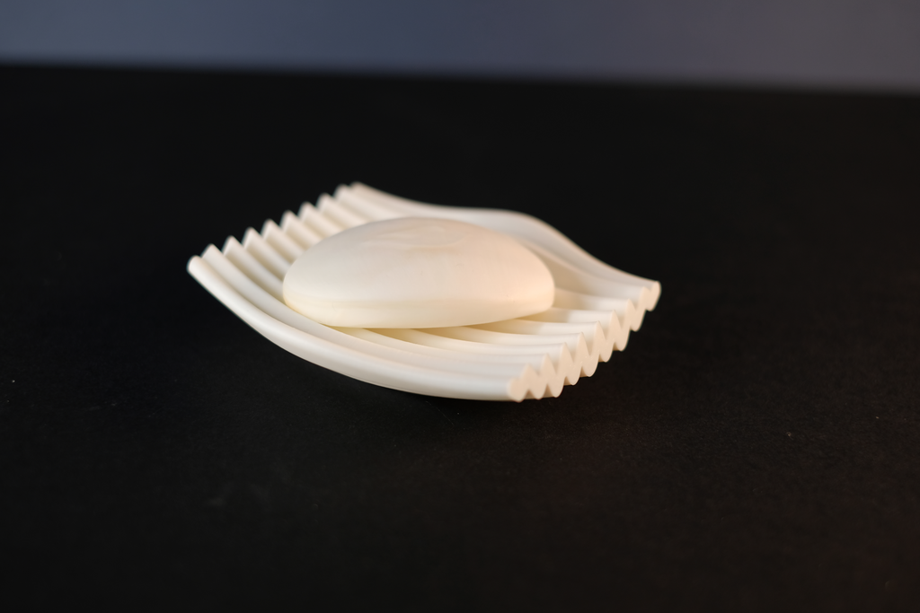 Side view of the white rippled soap dish holding a bar of soap.