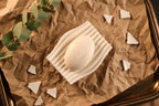 Top view of the white Rippl soap dish and soap on a warm textured background.