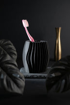 Moody dark bathroom scene with the black wave toothbrush holder and pink toothbrush