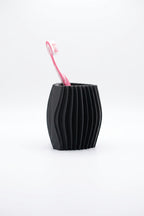 Black ribbed toothbrush organiser with one pink toothbrush on a clean white background