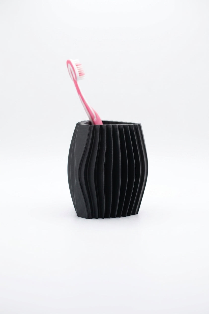 Black ribbed toothbrush organiser with one pink toothbrush on a clean white background