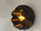 Close-up of a black rose-petal LED tealight holder casting a warm glow between the petals