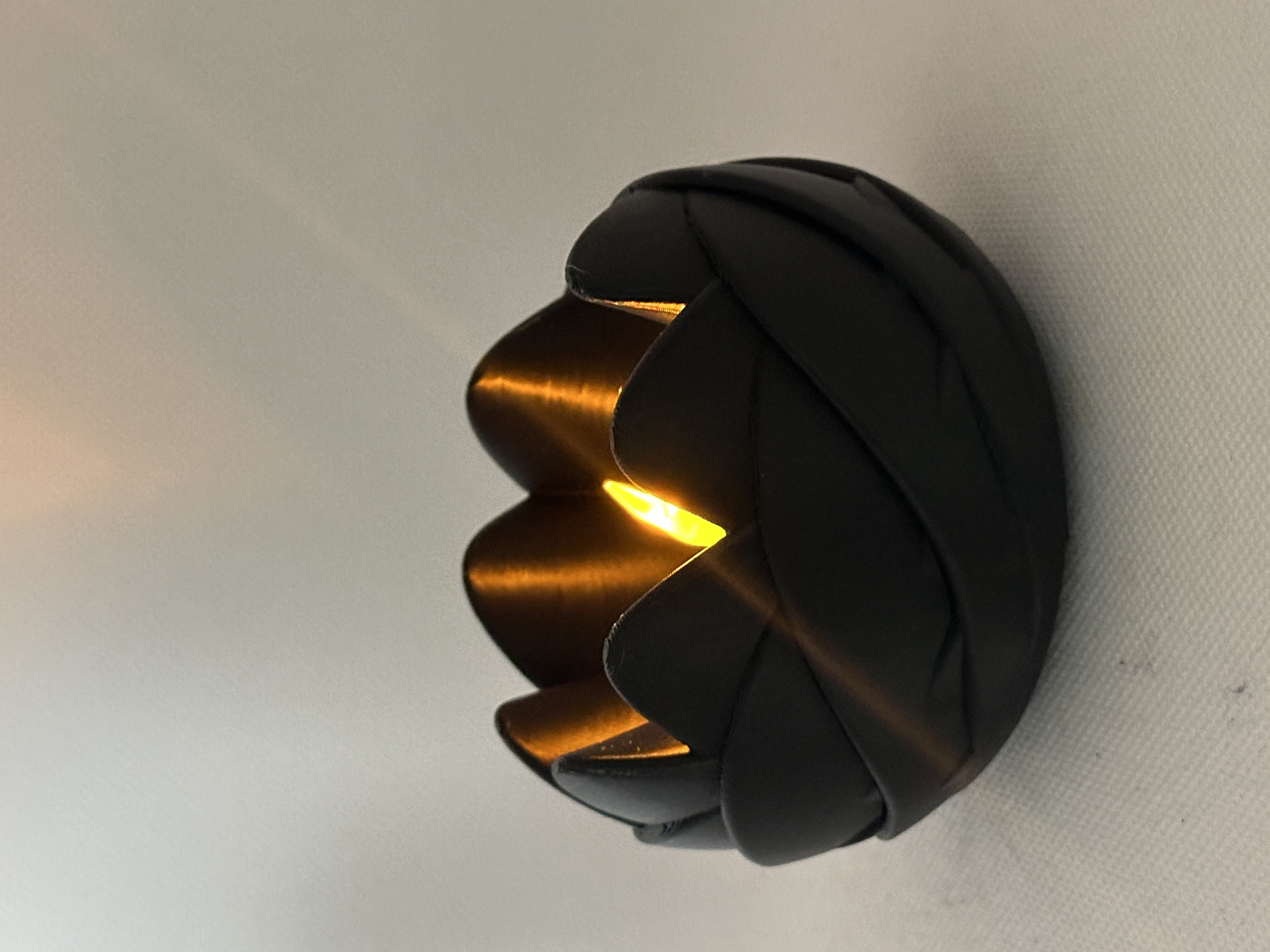 Black rose-inspired tealight holder glowing with an LED light in a close side view