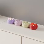 Lavender, pink, cream and red rose-shaped LED tealight holders arranged on a white cabinet