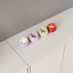 Top angled view of four rose-inspired LED tealight holders in lavender, pink, cream and red