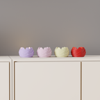 Four compact rose-inspired LED tealight holders displayed across a minimalist white cabinet