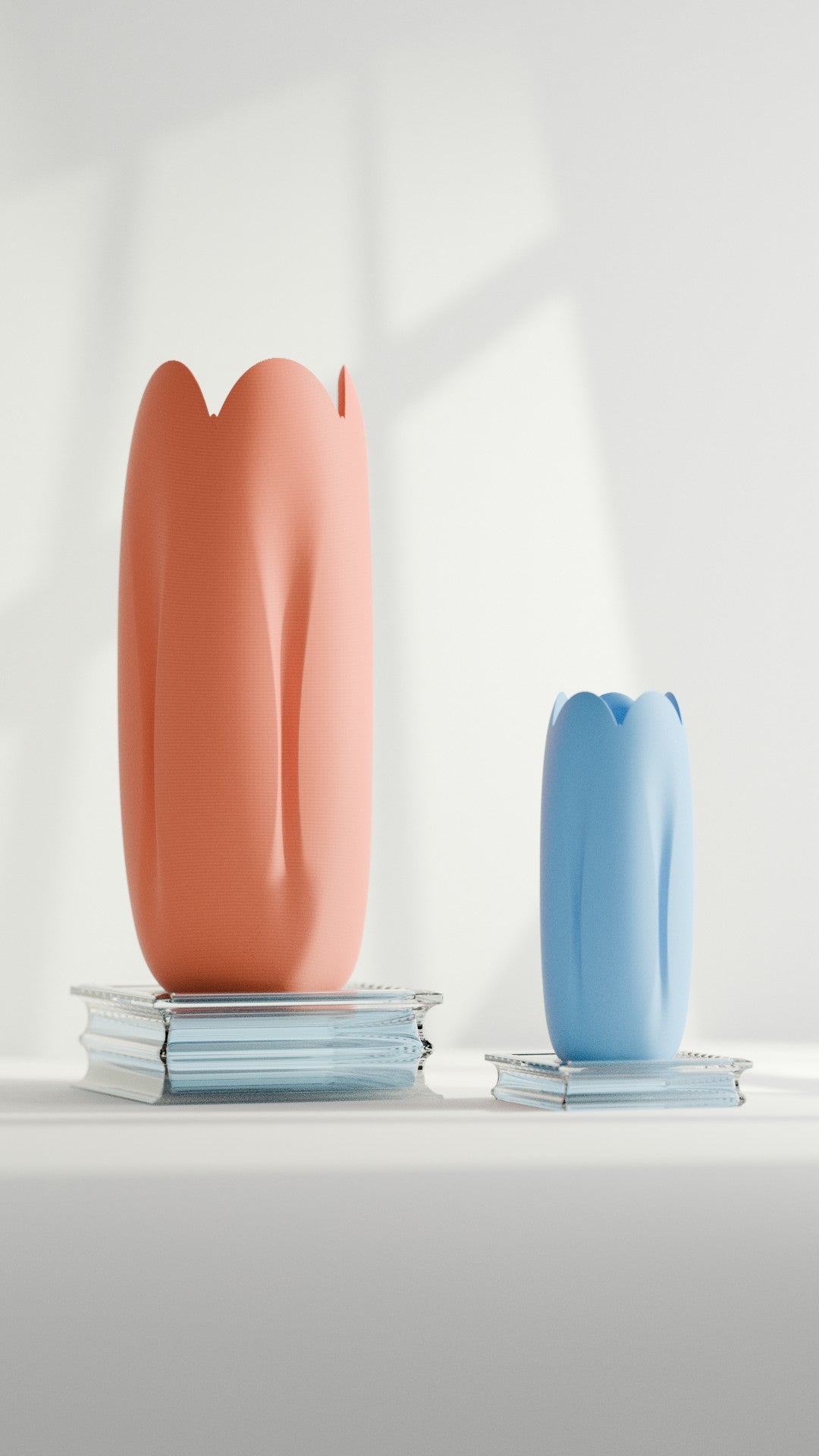 Coral and blue tulip-inspired vases styled on books beside soft window light
