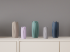 Tulip-inspired vases in five colours arranged across a minimalist cabinet