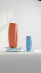 Two tulip-inspired decorative vases in coral and blue displayed on stacked books
