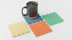 Set of colorful zigzag coasters with a mug on a light gray background