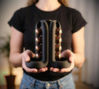 Black sculptural coffee pod holder held in both hands with capsules visible on opposing sides