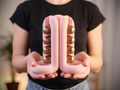 Pink three-way coffee pod holder shown in both hands with coffee capsules in the side rails