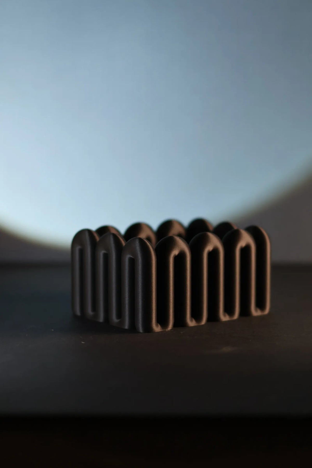 Black ribbed Wibble storage box on a dark tabletop in soft natural light