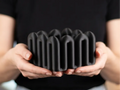 Black Wibble desktop storage box held in both hands against a dark shirt