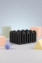 Black sculptural Wibble organiser shown with pastel geometric props
